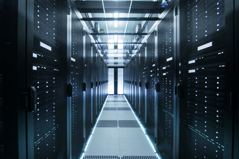 Looking down a data centre row of racks towards the lit door