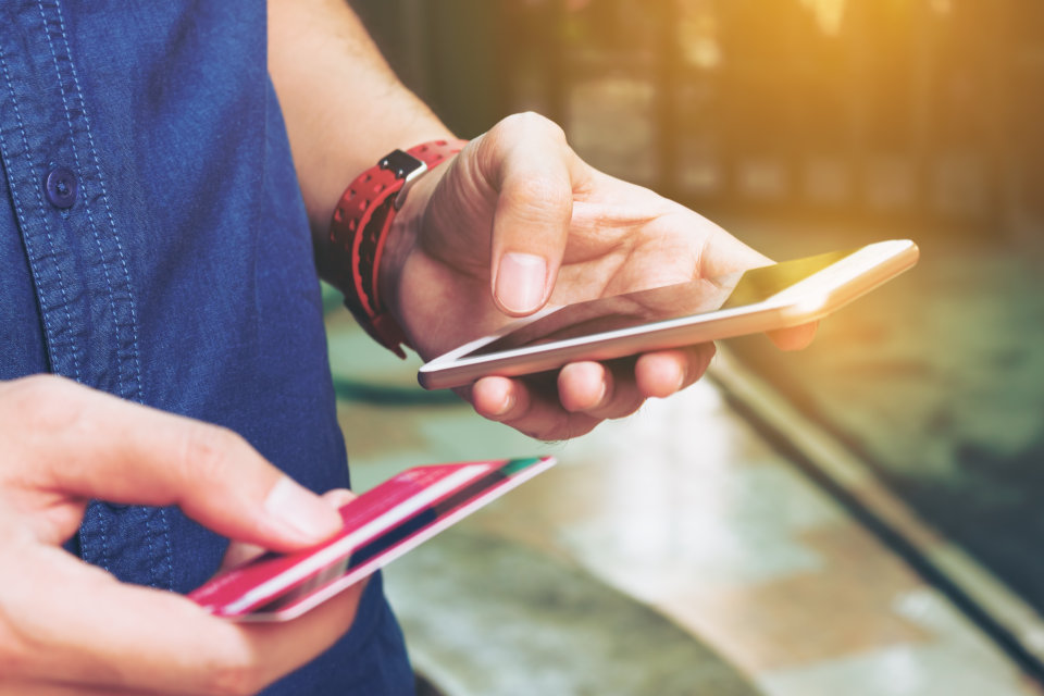 A person holding a bank card and mobile phone